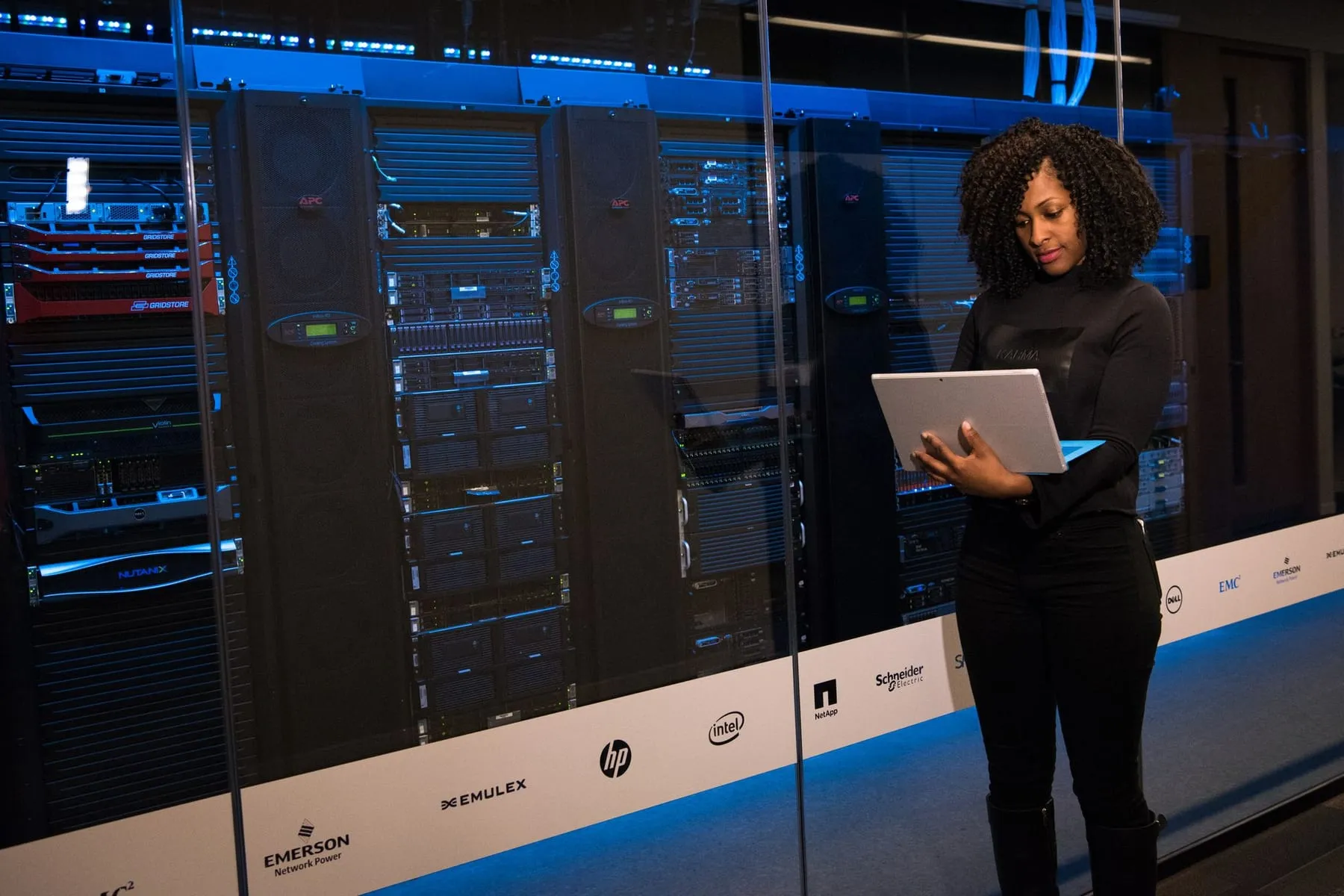 Engenheira com notebook acompanhando os servidores de um data center